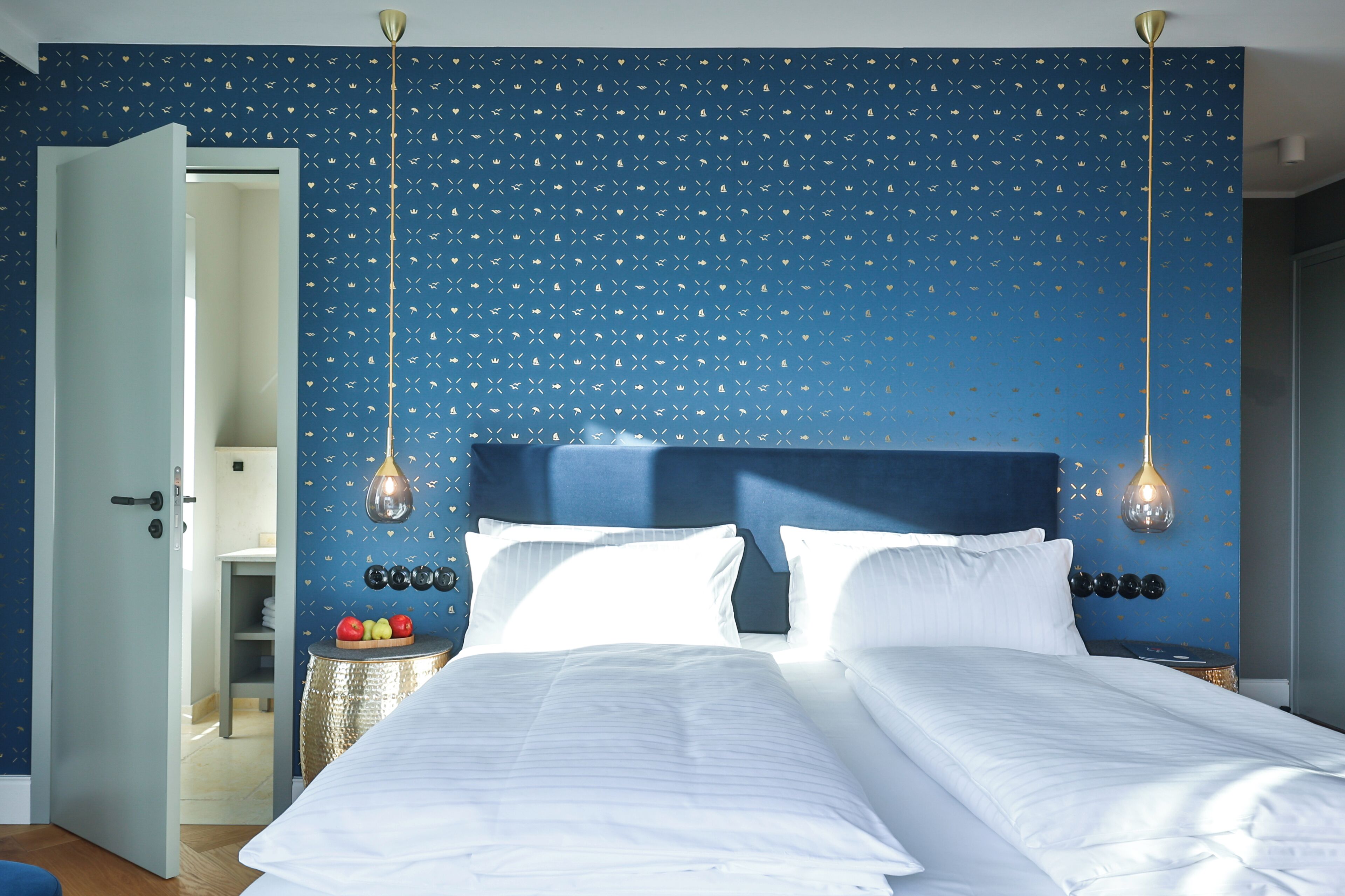 A bedroom with a bed, two bedside tables, a nightstand, and a wall with a blue pattern.