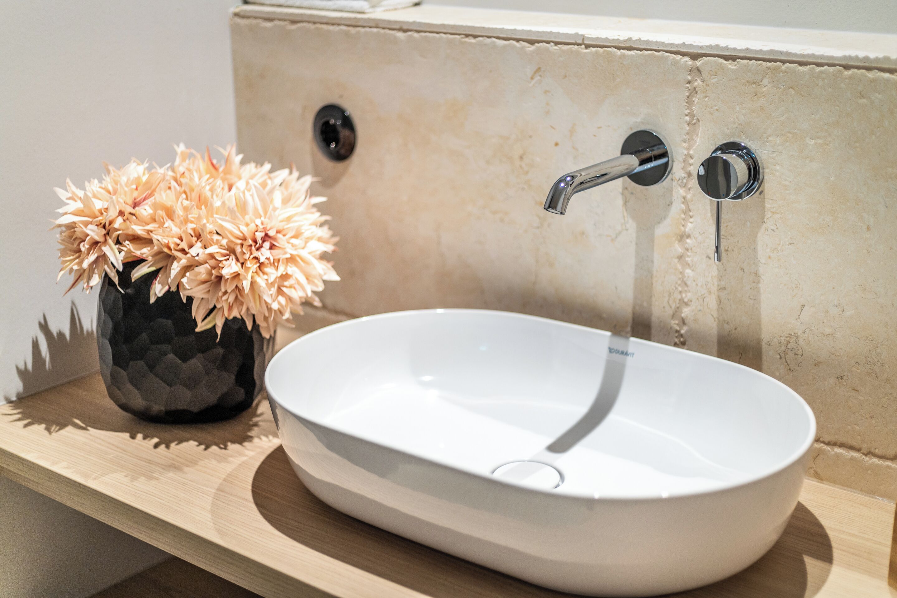 Un lavabo blanco ovalado con un solo grifo sobre una encimera de madera.