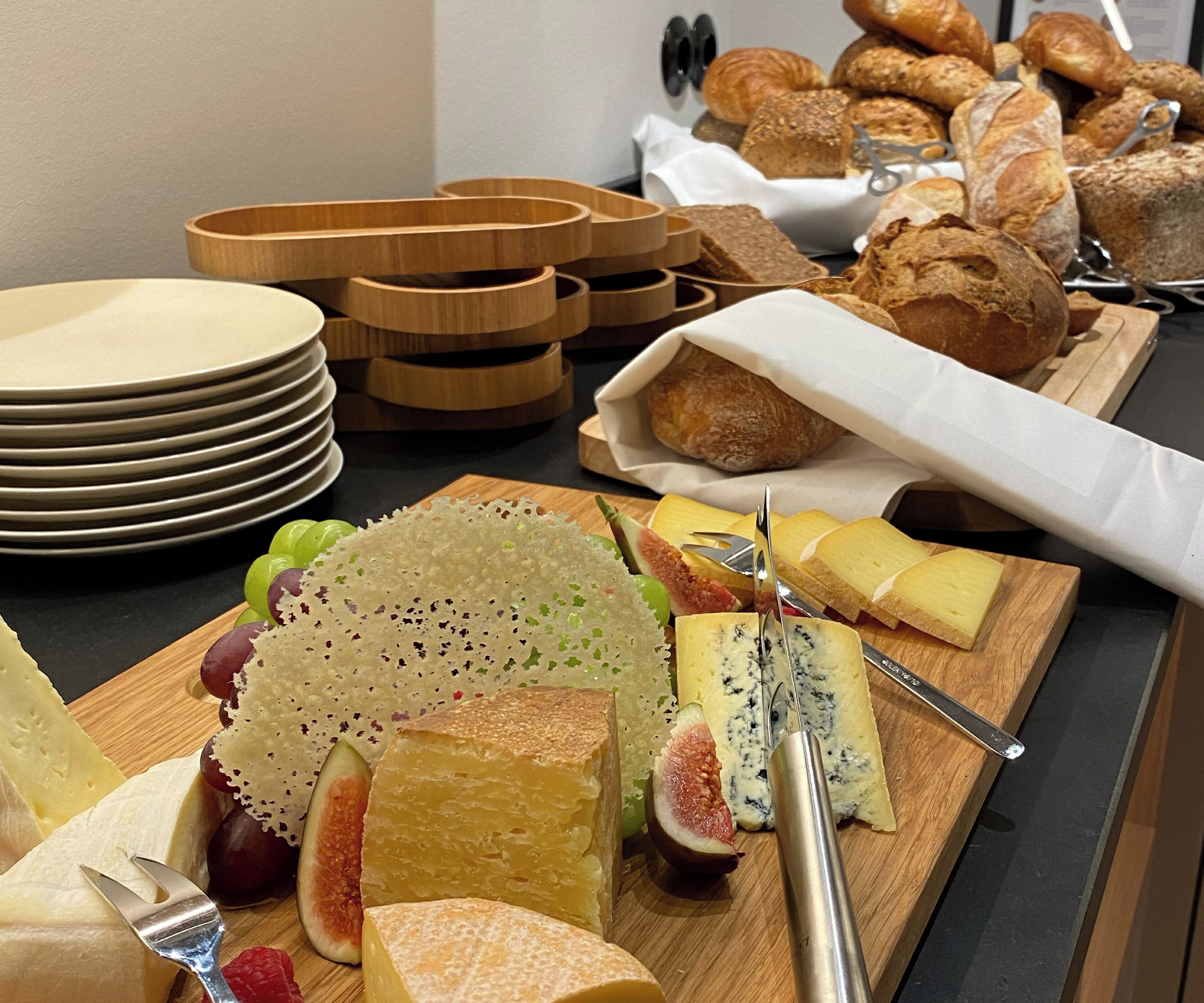 A buffet with various cheeses, fruits, and pastries.
