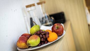 A plate of fruits including apples, pears, grapes, and oranges on a wooden table.