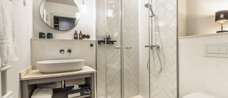 A modern bathroom with a glass-enclosed shower, a white sink, and a mirror above it.