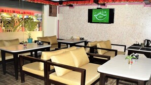 A restaurant with multiple tables and booths, a television mounted on the wall, and a view of the outside through the windows. - MeroStay 260 Hotel Rate (Kathmandu)