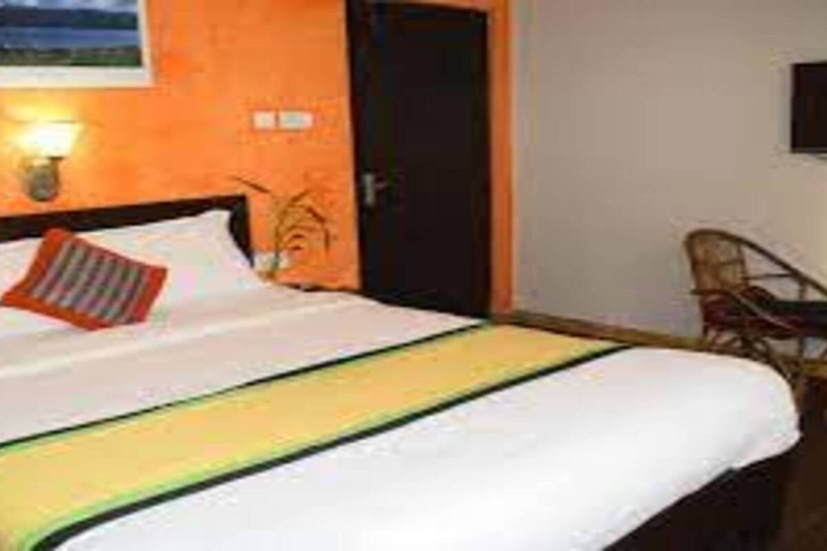 A hotel room with a bed, a chair, a desk, and a wall-mounted TV.