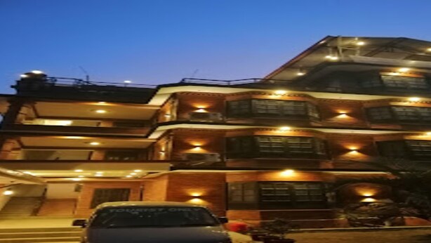 A multi-story building with multiple balconies and a car parked in front. - MeroStay 260 Hotel Rate (Kathmandu)