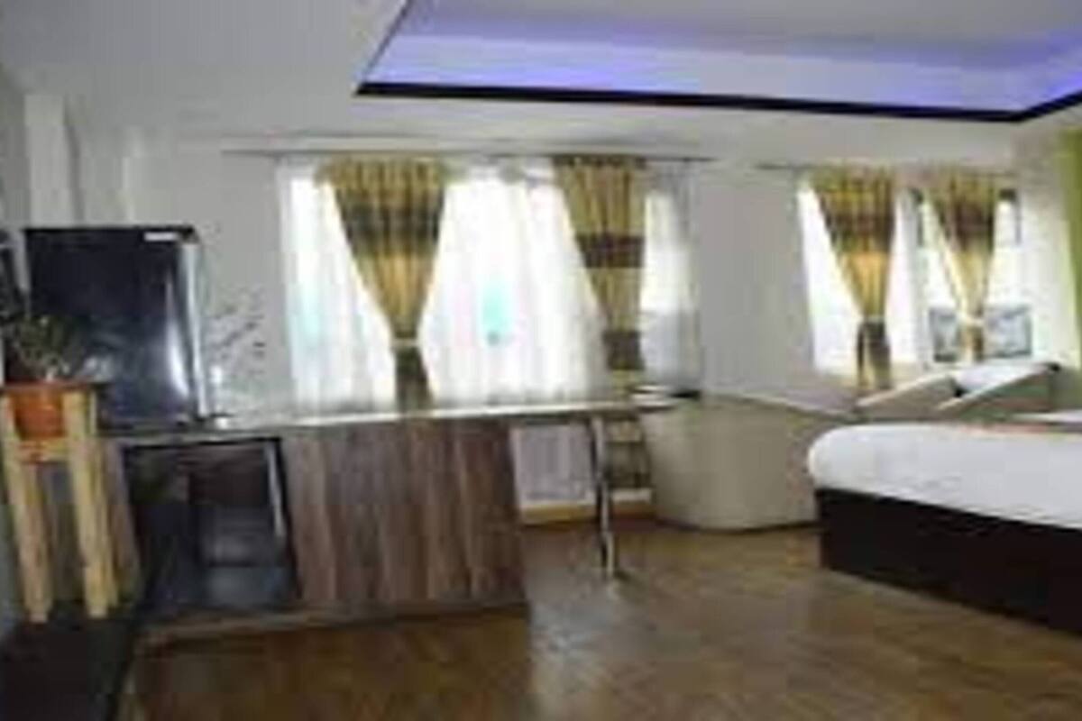 A hotel room with a bed, a desk, a chair, and a television.