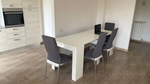 A modern kitchen with a white table and four chairs, a built-in oven, and a radiator.