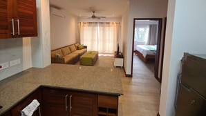 A modern kitchen with a granite countertop, wooden cabinets, and a ceiling fan. - Crystal Shores Self Catering Apartments - Seychelles (Mahé Island)