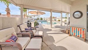 Un espacio al aire libre cubierto con sillones de mimbre, una piscina y un tablero de juego.