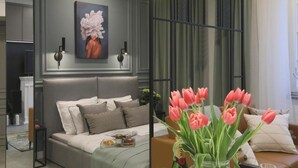 A modern bedroom with a bed, pillows, a nightstand, a vase of tulips, and a painting on the wall. - City Lights Skawińska (Kraków)
