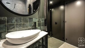 A modern bathroom with a large oval sink, a round mirror, and a shower area. - City Lights Skawińska (Kraków)