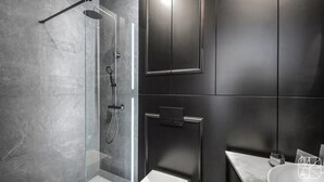 A modern bathroom with a glass-enclosed shower, dark cabinetry, and a marble countertop. - City Lights Skawińska (Kraków)