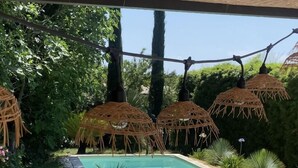 Ein Poolbereich mit Liegestühlen, einem kleinen Pool und strohgedeckten Sonnenschirmen.