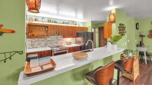 A modern kitchen with wooden cabinets, a marble countertop, and a central island with seating.