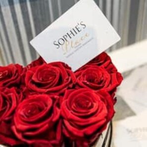 A bouquet of red roses with a card that reads "SOPHIE'S Flowers."