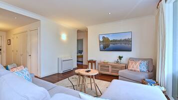 A living room with a sofa, a coffee table, and a painting on the wall.