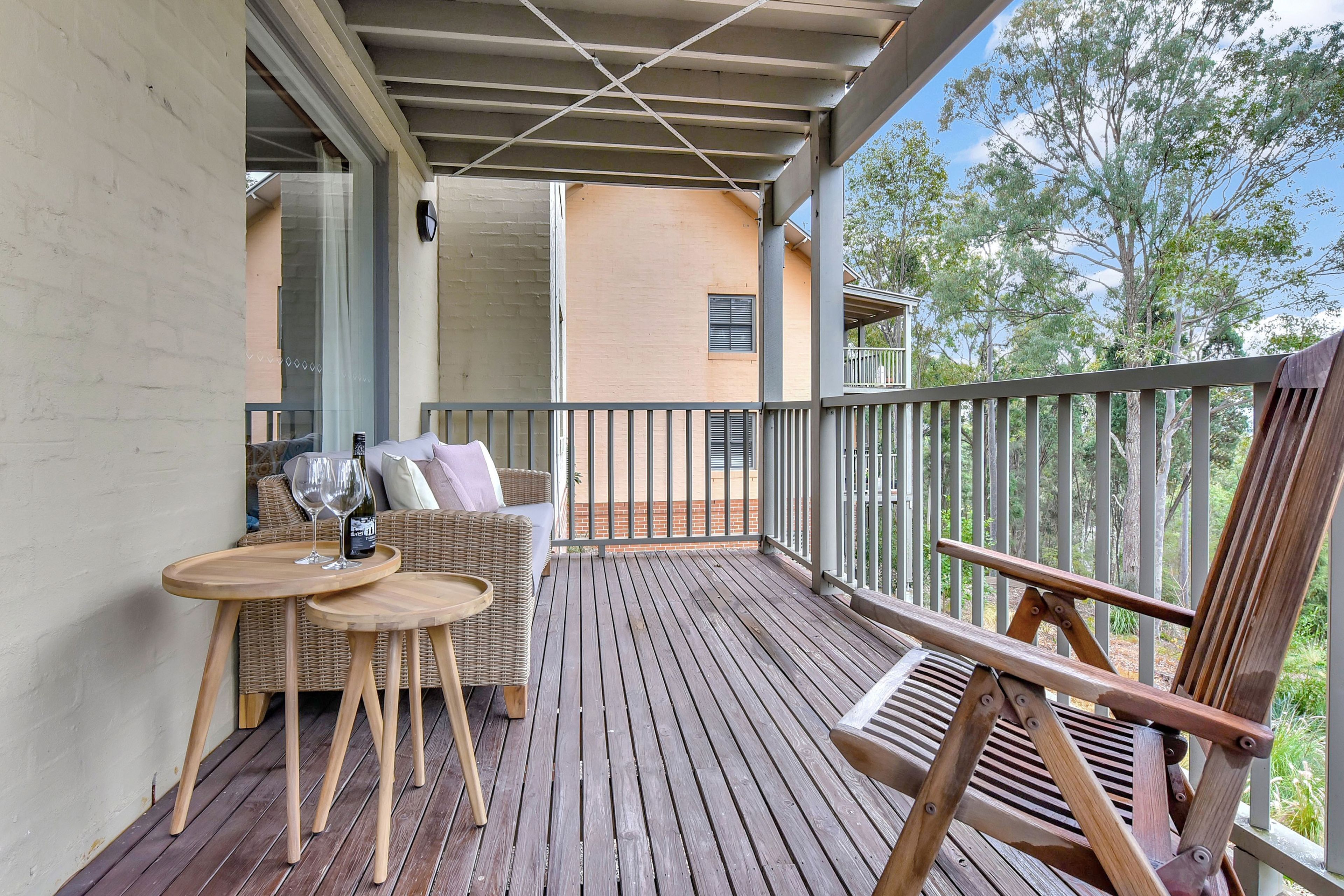 A wooden deck with outdoor furniture, including a wicker sofa and a wooden chair.
