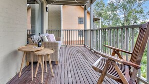 Eine Holzterrasse mit Gartenmöbeln, darunter ein Rattansofa und ein Holzstuhl.