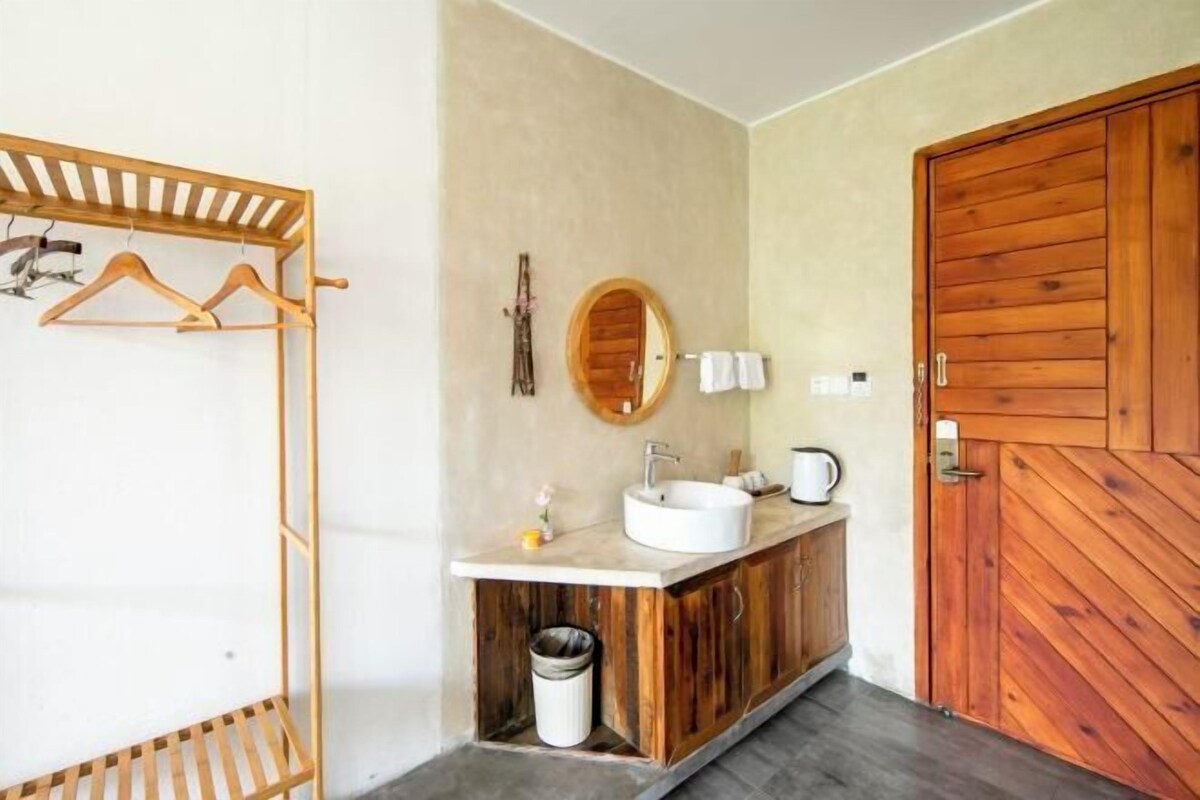 A bathroom with a wooden vanity, a round mirror, and a wooden door.