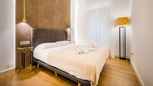 A modern bedroom with a bed, a bedside table, a lamp, and a wall with a geometric pattern. - In the heart of Seville by RentalSevilla (Sevilla)