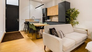 A modern apartment with a dining area, kitchenette, and a living room with a sofa and a plant. - In the heart of Seville by RentalSevilla (Sevilla)