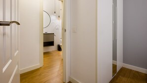 A hallway with a wooden floor leading to a bathroom with a toilet and a sink. - In the heart of Seville by RentalSevilla (Sevilla)