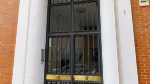 A building facade with a large window featuring metal bars and a brass door. - RentalSevilla in the Triana neighbourhood (Sevilla)