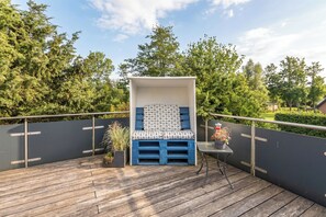 Um terraço com um banco azul e branco, uma mesa pequena e plantas em vasos.