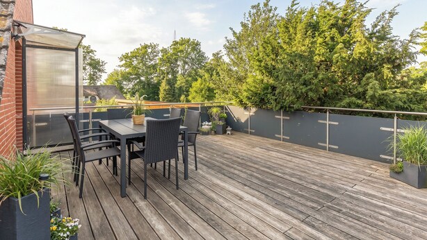 A wooden deck with a table and chairs, surrounded by potted plants. - Gode Sünn vacation apartment in Tating for up to 4 people (Tating)