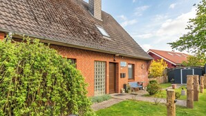 A brick house with a sloped roof, a small garden, and a wooden fence. - Gode Sünn vacation apartment in Tating for up to 4 people (Tating)