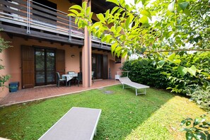 Um pátio com gramado, duas mesas e um banco.