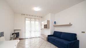 En moderne stue med en blå sofa, hvide vægge og et flisegulv.