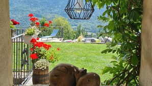 Una scultura in legno raffigurante un ippopotamo su un davanzale in pietra, un lampadario e una vista di un paesaggio montuoso attraverso un arco.
