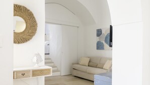 Una sala de estar moderna con un sofá blanco, un espejo redondo y una escalera que conduce a otra habitación.