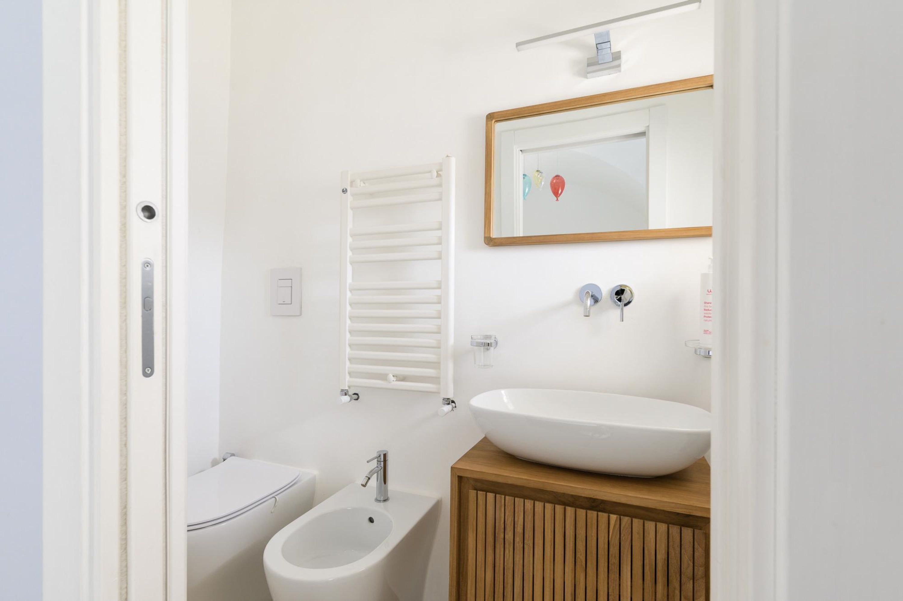Ein kleines Badezimmer mit Toilette, Bidet, Waschbecken und Spiegel.