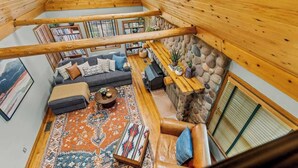 A cozy loft-style living area with a stone wall, a fireplace, and a large window. - Historic | Int Designed | DT Flag | Atrium | AC (Flagstaff)