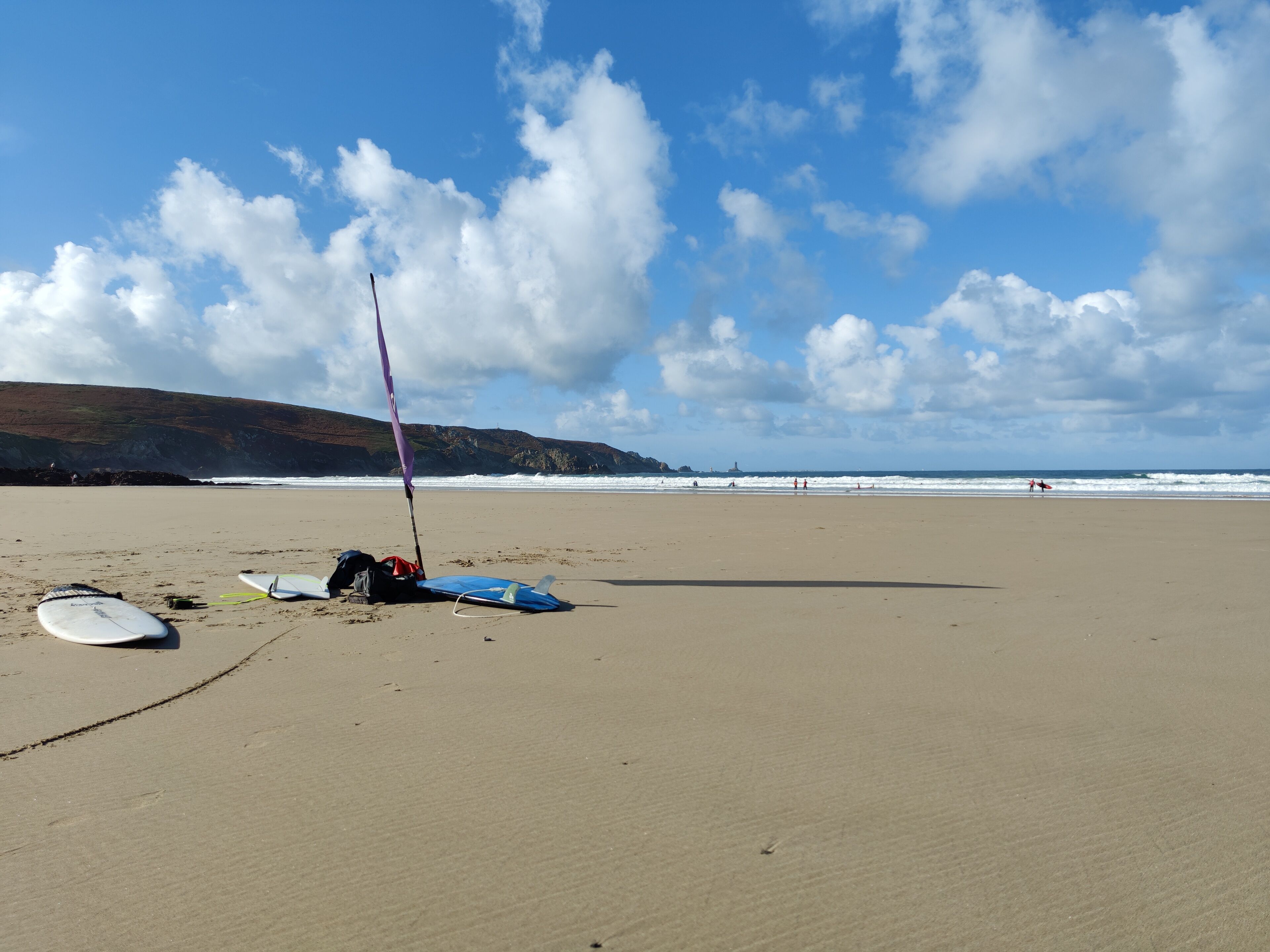 A beach with surfboards and a sail.