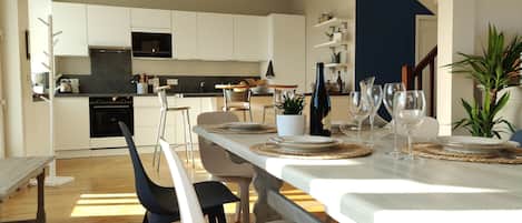 A modern kitchen with white cabinets, a black countertop, and a dining area with a white table set for two.