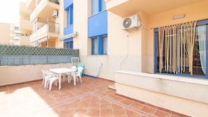 A patio with a table and chairs, a window with curtains, and an air conditioning unit.