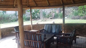 Un espacio de estar techado al aire libre con mobiliario de madera y suelo de ladrillo.