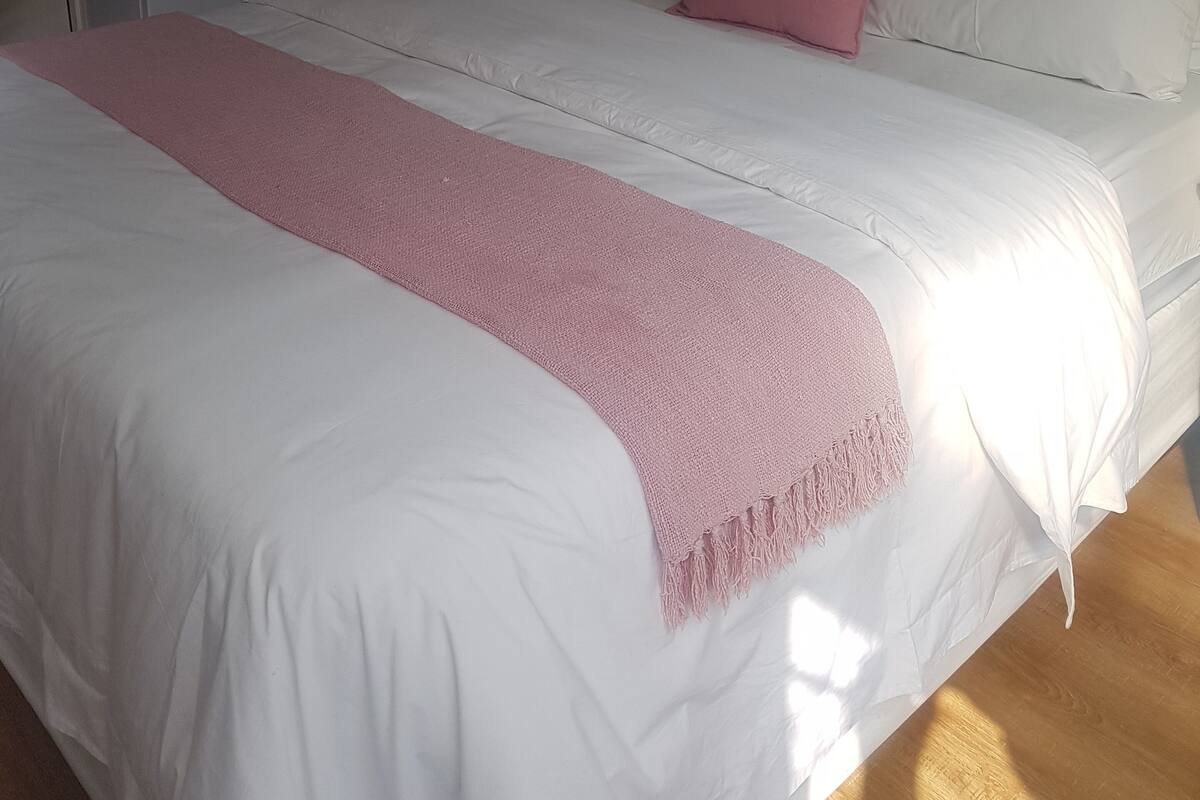 Une chambre à coucher avec un lit, une table de chevet, une lampe et un tableau accroché au mur.