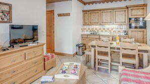 Una cucina accogliente con mobili in legno, un tavolo da pranzo e un televisore su un comò.