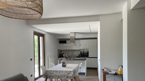 A modern kitchen with white cabinets, a central island, and a dining area with a table and chairs. - The house of roses (Passignano sul Trasimeno)