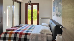 A bedroom with a bed, a radiator, a window, and a door. - The house of roses (Passignano sul Trasimeno)