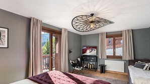 A bedroom with a bed, a desk, a chair, and a television.