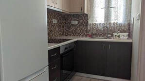 A compact kitchen with dark cabinets, a white refrigerator, and a tiled backsplash. - Apartment 'Ventus Pandora' with Sea View, Wi-Fi and Air Conditioning (Lefkada)