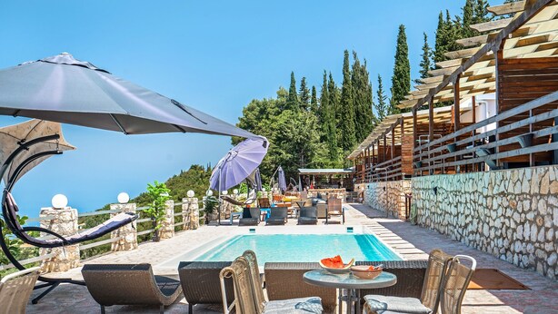 A poolside area with wicker chairs, a table, and umbrellas. - Apartment 'Ventus Pandora' with Sea View, Wi-Fi and Air Conditioning (Lefkada)