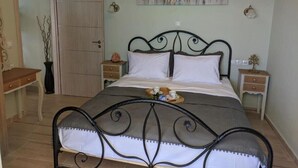A bedroom with a bed, bedside tables, a desk, and a painting on the wall. - Apartment 'Ventus Pandora' with Sea View, Wi-Fi and Air Conditioning (Lefkada)