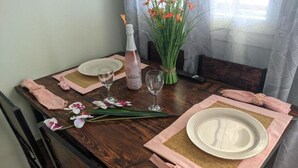A dining table set with plates, glasses, a bottle, and flowers. - Apartment 'Ventus Pandora' with Sea View, Wi-Fi and Air Conditioning (Lefkada)