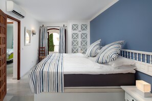 Quarto com cama, mesa de cabeceira e vista para o exterior.