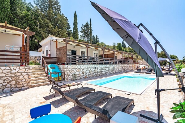 A poolside area with lounge chairs, a table, and a pergola with a canopy.